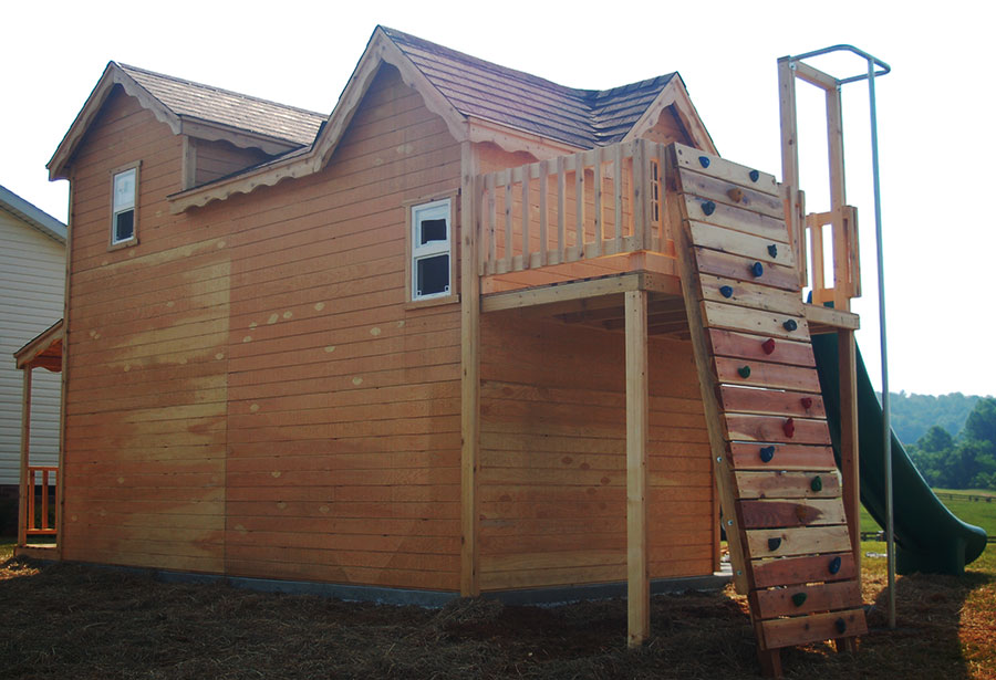 Image of wood playhouse with slide and rock wall